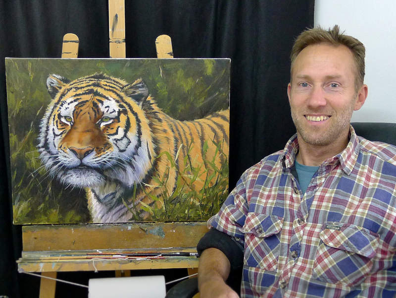 Chris Chalk sitting beside his painting easel in his Pembrokeshire art studio