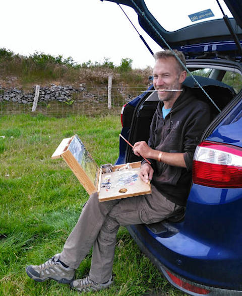 welsh artist chris chalk painting outdoors in Wales using a pochade box whilst sitting in the back of a car. 
