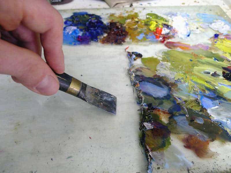 Dirty palette of the artist. Oil paints on a glass palette. Stock Photo